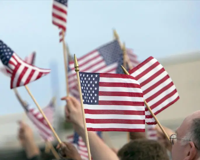 A group of people holding american flags in the air.