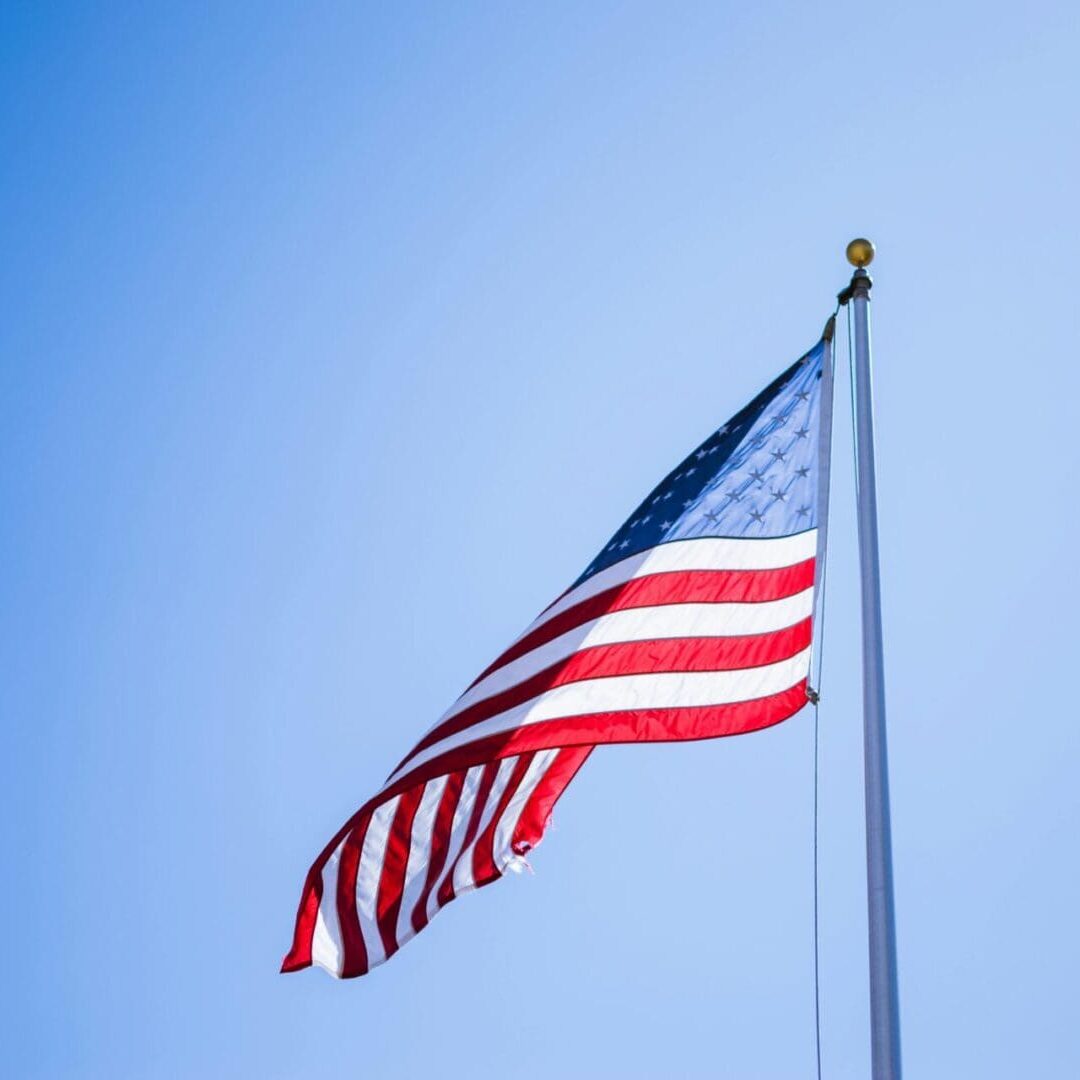 A flag flying in the wind on top of a pole.